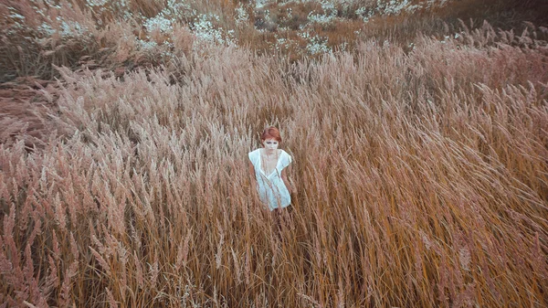 Kvinnan i en vit klänning stannar i fältet — Stockfoto
