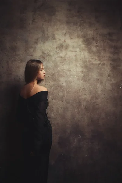 Het slanke meisje staat in de buurt van prachtige muur — Stockfoto