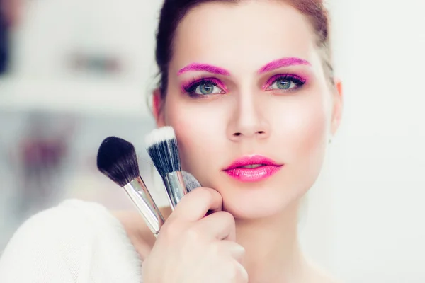 The makeup artist holds powder brushes