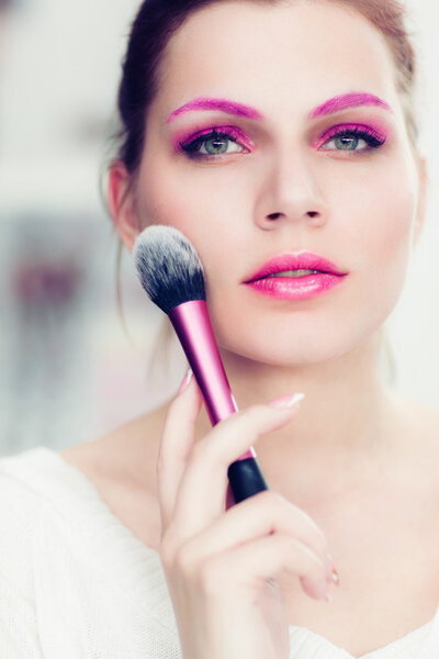 Визажист держит румяную кисть.
