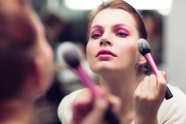 Девушка с ярко-розовым макияжем наносит румяна — стоковое фото