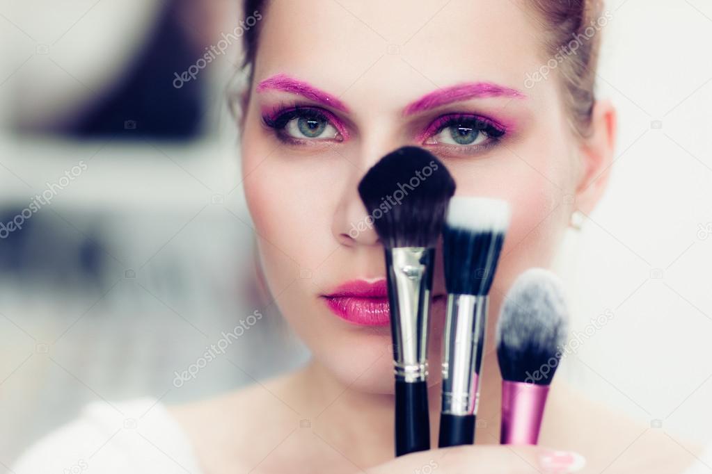 The makeup artist holds powder brushes