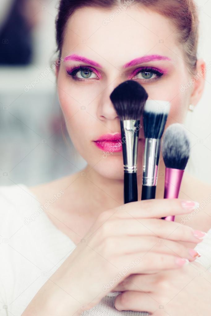 The makeup artist holds powder brushes