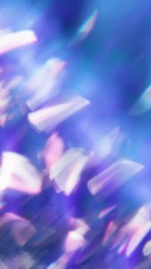 Dikey video. Parlak partiküller. Ray yansıması. Parlak beyaz kıvılcımlar parıldar. Lens parıldar. Mavi mor renk arka planda parlar..