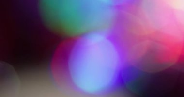 Bokeh ışığı. Renkli sızıntı. Mor kırmızı, çözünmüş yeşil halkalar koyu siyah arka planda akar. Spektrum canlı yansıma soyut doku.