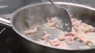 Yemek pişirme süreci. Fırlatma tavası. Elektrikli ocakta sıcak et yemeği hazırlıyorum. Buharda pişirilmiş çelik tencerede yemek kaşığıyla karıştırılmış tabak..