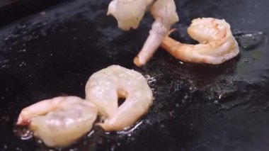 Karides hazırlıyorum. Mutfak süreci. Cımbızlar siyah ızgara tavasında deniz ürünleri çeviriyor. Aromatik kıtır kıtır kızarmış kabuklu aperatif..