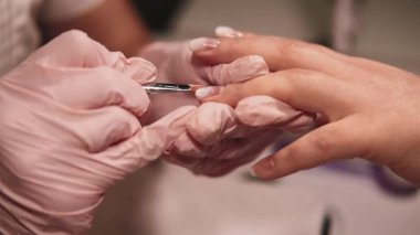 Manikür servisi. Tırnaklarına dikkat et. Kadın, koruyucu lateks eldivenli güzellik uzmanı tarafından profesyonel el tedavisi görüyor..
