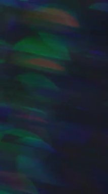 Dikey video. Odaklanamayan ışık patlaması. Parıltı sızıntısı. Bulanık gökkuşağı çok renkli mercek soyut bokeh arka planda yanıp sönüyor.