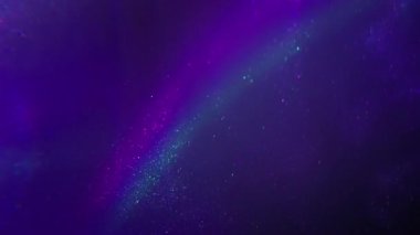 Flüoresan ışını. Parlak akış. Odaklanmamış mor mavi renk parıltısı soyut koyu siyah ışık arka planında ışıldayan neon gökkuşağı parçacıkları.