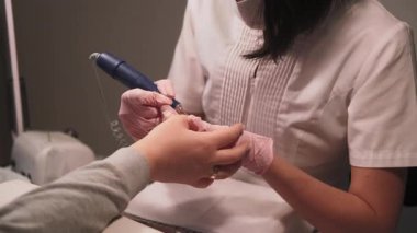 Tırnak bakımı. Matkap cilası çıkarıcı. Kadın manikürcü el elektrikli aletle eski jel kılıfını kadın parmak hijyen tedavisinden temizliyor..
