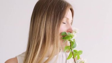 Kadınsı güzellik. Huzur içinde. Çekici yüz, rahatlamış kadın beyaz fotokopi alanı arka planında çiçek çiçeği, yeşil dal yiyor..