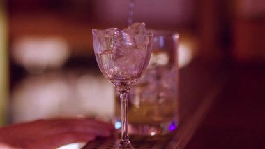 Güzel içki. Buz küpü içeceği. Barmen tezgahta soğuk aperatif bardağı yapıyor. Profesyonel uzun kaşıkla el yapımı kokteyl..