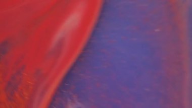 Boya sıvısı. Renk akışı. Bulanık turuncu mor eflatun, parlak pigment kimyasal su parçacıkları soyut arkaplanda yayılıyor..