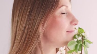 Çiçek ilhamı. Huzur içinde. Çekici yüz, rahatlamış kadın. Çiçek açan yasemin çiçeğinin tadını çıkarıyor. Sanatın beyaz arka planında yeşil dal..