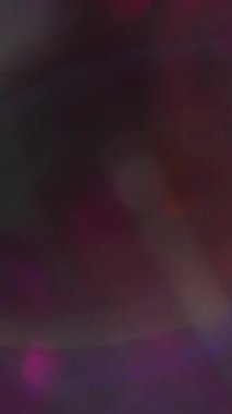 Dikey video. Odaklanmamış renk yansıması. Daire şeklinde bir bakış. Bulanık bokeh ışık arka planında yeşil mavi turuncu kaleydoskop mercek parlaklığı.