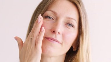 Yüz kolajeni. Cilt kozmetiği. Beyaz makyajdan önce kadın cilt kremine nemlendirici krem süren bir kadın..