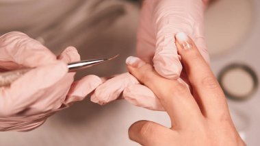 Çıplak manikür. Jel cilası. Kadın güzellik uzmanı. Eldiven giymiş. Kuaför salonu prosedürü için oje sürüyor..