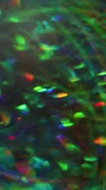 Dikey video. Bulanık parlayan ışık. Sanat rengi. Görkemli yeşil turuncu kaleydoskop mercekleri Bokeh soyut arka planında parıldıyor..