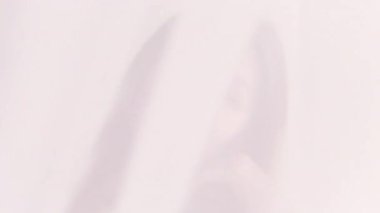 Kadınsal rahatlama. Kadın doğası. Kendinden emin, uzun saçlara dokunan, beyaz fotokopi arkaplanındaki perdenin arkasında gülümseyen bir kadın..