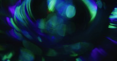 Bokeh ışığı. Renkli sızıntı. Mavi yeşil çözünmüş daireler koyu siyah arka planda akar. Spektrum canlı yansıma soyut doku.