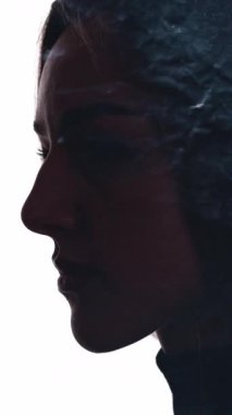 Dikey video. Aydınlanma enerjisi. Ruhsal iyileşme. İç huzuru. Etkilenen kadın, beyaz renkte yüzen parıltılı tozla çifte maruz kalıyor..