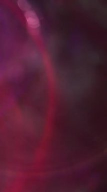 Dikey video. Görüntü kıvılcımlar saçar. Bokeh daireleri. Çok renkli kırmızı, mavi, mor, parlak mercek koyu soyut arkaplanı açıyor..