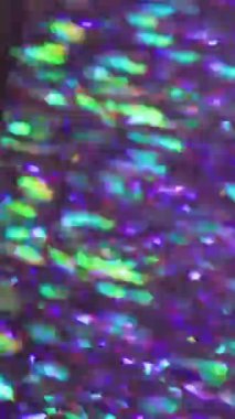 Dikey video. Bulanık neon parıltısı. İşaret fişeği. Kaleydoskop sarı yeşil kırmızı mor lens açık arkaplanda yanıp sönüyor.