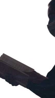 Dikey video. Karantina çalışması. Okuma hobisi. Parlak toz çift pozlama profil silueti yüz maskeli kadın açık kitap izole beyaz boşluk arkaplan.