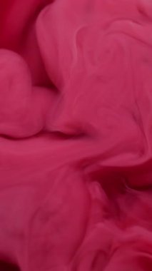 Dikey video. Duman boyası. Akrilik pigment. Odaklanmamış pembe kırmızı kırmızı su rengi kimyasal partiküller soyut sanat arka planında büyüyen sis özü.