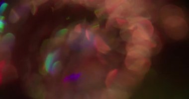 Mercek prizması bokeh. Işıl ışıl parlıyor. Siyah arka planda renkli spiral parıltı. Mor kırmızı yeşil neon yuvarlak soyut ışık.