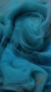 Dikey video. Sıçrama sanatı. Sıvı doku. Odaklanmamış mavi turuncu renkli duman parlak akrilik madde kimyasal mürekkep soyut arkaplanda yüzüyor.