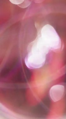 Dikey video. Dönen daire. Bulanık, parlak. Bokeh hafif kaleydoskop arka planında çok renkli çember lensleri parlıyor.