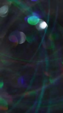 Dikey video. Bulanık renk değişimi. Soyut ışıltı. Göz kamaştırıcı ışıl ışıl ışıl, aydınlık mercek Bokeh açık renk siyah arka planda parlıyor..