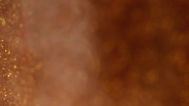 Bulut dumanı. Parıltılı doku. Bulanık sarı altın rengi mürekkep kıvrımlı su sisi pulları soyut koyu siyah buhar arka planında hareket ediyor..