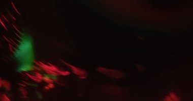 Girdap bulanıklığı. Parlak akış. Siyah soyut arkaplanda kırmızı yeşil ışık var. Açık renk sanat eğrisi koyu boş alanda parlar.