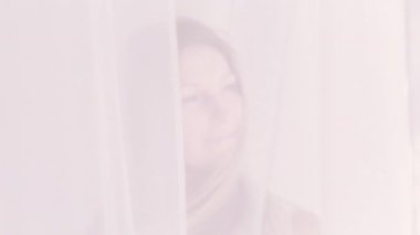 Çekici bir kadın. Özgürlük ilham kaynağı. Güzel, rahat kadın uzun saçlara dokunuyor, beyaz perdenin arkasında gülümsüyor..