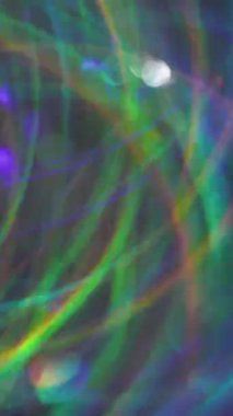 Dikey video. Renkli ışıltı. Bulanık, ışıltılı bir doku. Yeşil mavi turuncu çizgili kaleydoskop yanıp sönen mercek flaşlı arka plan.