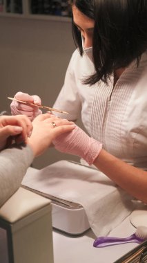 Profesyonel manikür. Tırnak törpüsü. Güzellik teknisyeni kadın eldivenler, akrilik tırnak bakımı rutin kozmetik tedavisinde mercimek tahtası kullanıyor..