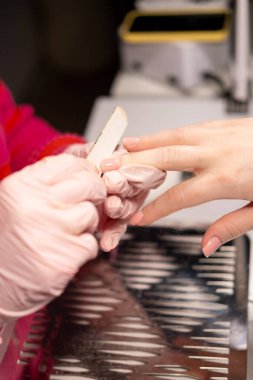 Modern manikür. Tırnak bakımı. Profesyonel kadın manikürcü, koruyucu eldiven verdi müşteri güzellik prosedürü sırasında zümrüt pano kullanıyor..