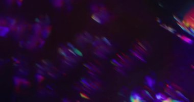 Bulanık holografik ışık. Işın prizması. Soyut siyah arkaplanda gökkuşağı renkleri parıldıyor. Neon mor yeşil kırılma lensi.