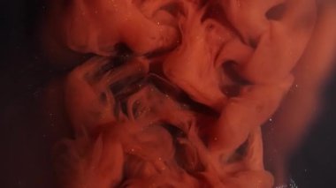 Turuncu boya damlası. Işıldayan arka plan. Koyu siyah akrilik soyutlama üzerinde yüzen parlak renk girdap dumanı sıvısı..