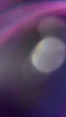 Dikey video. Odaklanmamış disko rengi. Parıltı parlıyor. Neon ışıklı mercek ışıltısı, bokeh arkaplanlı bulanık bir şekilde dönen optik daireler..