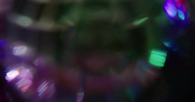 Işıldayan top bokeh. Kaçak aydınlatma. Siyah üzerine neon renkli cam küre kaleydoskop dönüşü. Mor yeşil kırmızı soyut bulanık arkaplan.