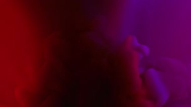 Mistik duman. Mürekkep buharı. Mor kırmızı ışık suyunda parlak boya dalgası. Fantezi damla patlaması soyut gölge renk arkaplanı.