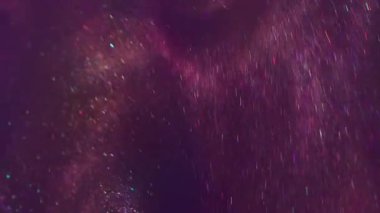 Görüntü mürekkebi. Parlak ışık. Odaklanmamış mor eflatun rengi parlak desen ışıldayan parçacıklar soyut sanat arka planında bokeh etkisi ile birlikte akıyor.