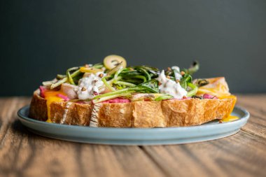 Gurme tostu. Besleyici yiyecekler. Zeytin yeşili etli zanaatkar ekmeği tabakta et bırakır. Parlak hardal soslu porsiyon yemeği.