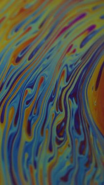 Dikey video. Yakıt dökülüyor. Yanardöner sanat. Soyut arkaplanda yüzen bulanık mavi mor renkli kimyasal boya..