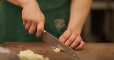 Baharatlı yemek hazırlıyorum. Sarımsak doğruyorum. Eller soyulmuş taze karanfilleri keser. Mutfak tahtasındaki lezzetli yemekler için gerekli malzemeleri dilimleyen şef..