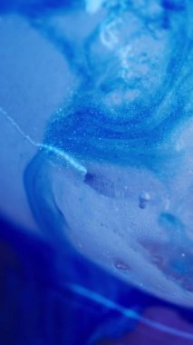 Dikey video. Boya dökülmüş. Buzlu arka plan. Odaklanmamış mavi renkli, ışıldayan damlacıklar hafif akrilik soğuk soyutlama üzerinde yüzen buz damlacıkları..